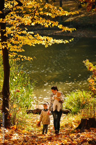 Happy family concept. Mother and children having fun in the autumn forest next to a lake. Motherhood concept