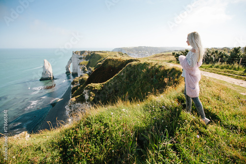 Girl hiking and taking picture of Etretat cliffs and Atlantic ocean in Etretat, France