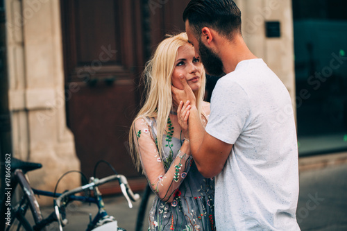londe girl and Hipster handsome man with beard hugging and kissing on the city streets