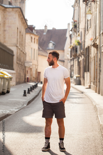 Hipster handsome male model with beard wearing white blank t-shirt with space for your logo or design in casual urban style