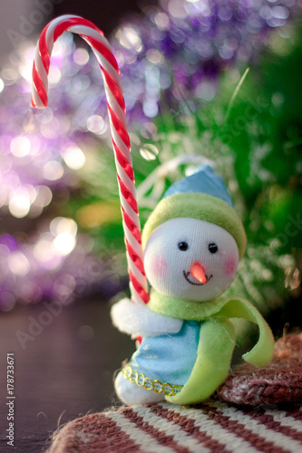 Toy snowman holding christmas candy cane in hands.