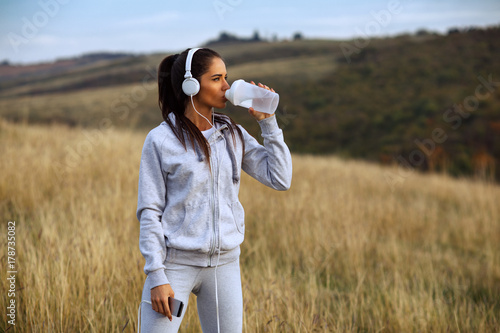 Young women drink water after jogging in nature
