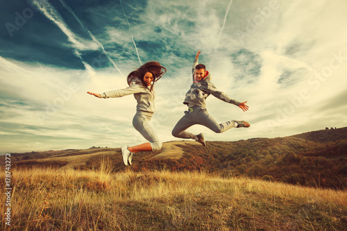 Happy young couple jump in the air in nature