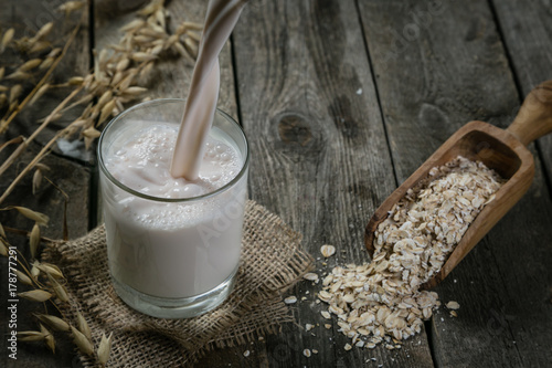 Pouring oat milk on rustic wood background