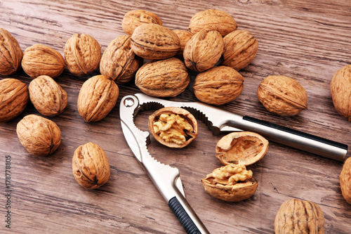 Walnut kernels and whole walnuts on brown wooden table.