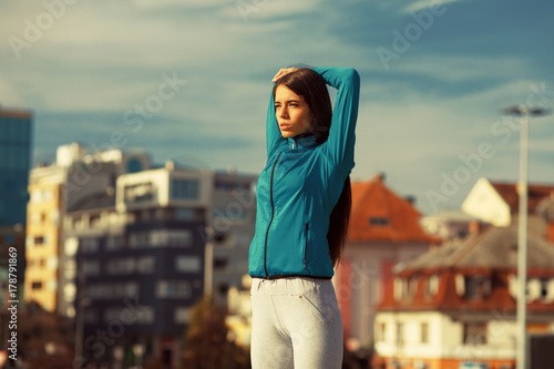 Young sport woman stretching hands in the city