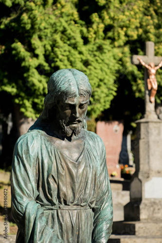 Zdjęcie XXL nagrobek z bronse Jesus otoczony zielenią i ciepłym słońcem lśniącym zza drzew