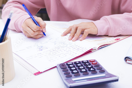 student hand writing with calculator at home or school