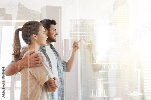 happy couple looking through window at new home