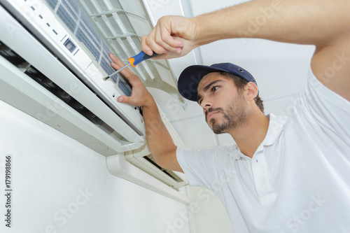 portrait of mid-adult male technician repairing air conditioner