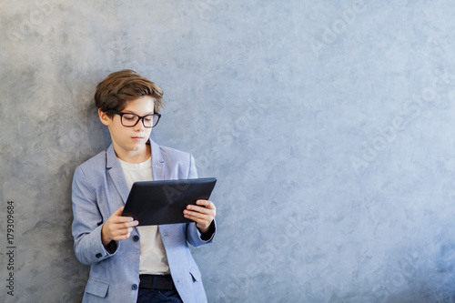 Teen schooler boy in eyeglasses holds tablet PC