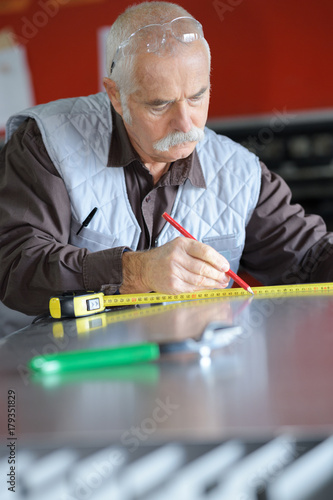 senior man installing and measuring a shower box at home