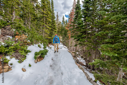Tourist with backpack hiking on snowy trail