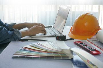 architect working on laptop with construction tools and blueprint - business and industrial concept