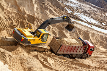 Excavator Loading Dumper Truck at sunny day