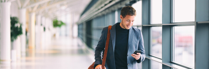 Man holding phone - young businessman using smartphone in airport. Casual urban professional business man texting cellphone happy inside office banner panorama with copy space on background.