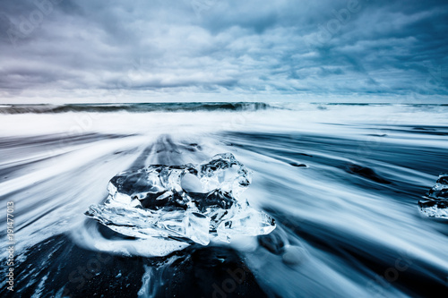 Plakat Duże kawałki góry lodowej, które błyszczą na czarnym piasku. Lokalizacja miejsce Jokulsarlon, Park Narodowy Vatnajökull, Islandia.