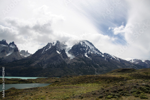 Plakat ośnieżone górskie szczyty torres del paine w chmurach i turkusowe jezioro