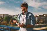 Young happy man using a smartphone in the city
