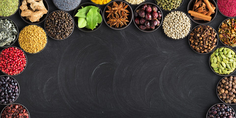 set of spices on  black table with empty space for text. Colorful seasoning against  background of blackboard