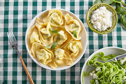 Plakat Napowietrznych obraz tradycyjnych włoskich ravioli z serem ricotta i tagliatelle szpinaku na stole pokryte zielonym obrus w kratkę