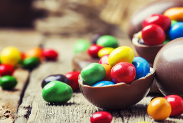 Easter composition with chocolate eggs and colorful candy, vintage wooden background, selective focus