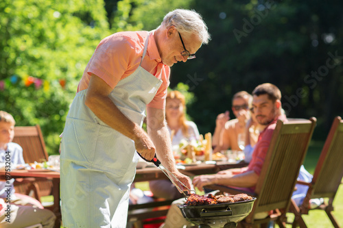 Zdjęcie XXL Jedzenie, ludzie i rodzinny czasu pojęcie - starszego mężczyzna kulinarny mięso na grilla grillu przy lato ogródu bbq przyjęciem