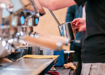 Barista steaming milk for coffee using machine, cropped