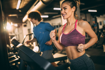 Horizontal photo of attractive woman jogging on treadmill at health club.
