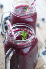 Berry smoothie in glass with blueberries, mint and cocktail tube