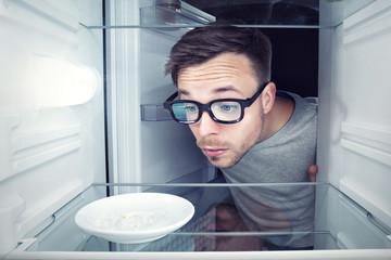 Student schaut in einen leeren Kühlschrank