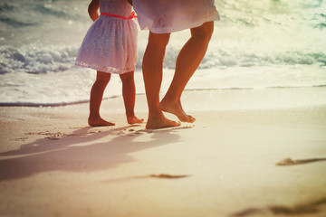 Mother with little daughter walk on sand beach