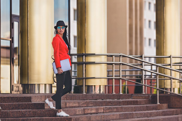 Happy hipster young woman working on laptop outdors. Student girl using laptop in university campus. Toned image.