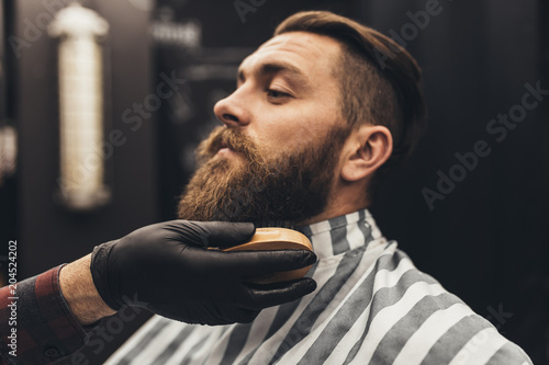 Hipster young good looking man visiting barber shop. Trendy and stylish beard styling and cut. © hedgehog94