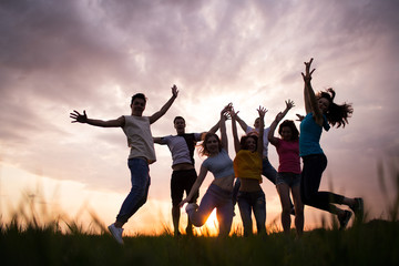 Young people jumping against the sunset sky