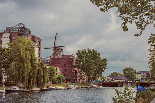 Plakat Duży zalesiony kanał z ceglanymi budynkami, cumować łodziami i chmurnym niebem w Amsterdam. Słynie z ogromnej aktywności kulturalnej, zgrabnych kanałów i mostów. Północnej Holandii. Retro vintage filtr.