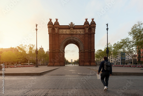 Zdjęcie XXL Turystyczny zwiedzający Bacelona Łuk De Triomf podczas wschodu słońca w mieście Barcelona w Catalonia, Hiszpania. Łuk jest zbudowany w czerwonawy mur w stylu neo-mudejar