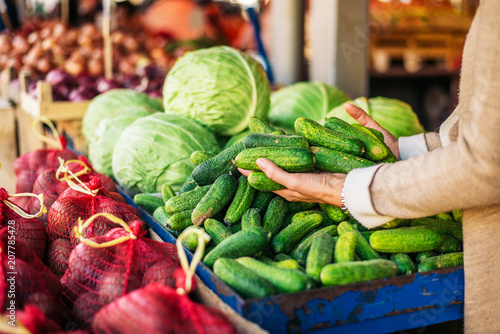Фото: Buying fresh cucumbers at farmers market. Unrecognizable person. Buying fresh cucumbers at farmers market. Unrecognizable person.