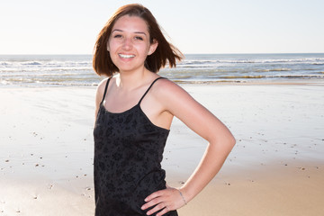 Portrait of laughing girl standing at beach on sunny day