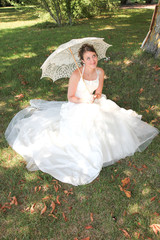 beauty bride woman sit on green grass with umbrella on marriage day