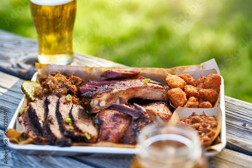 Фото: tray of smoked meats texas bbq style outside on picnic table on sunny summer day tray of smoked meats texas bbq style outside on picnic table on sunny summer day