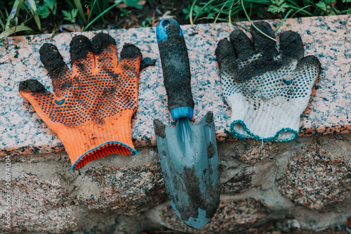 Фото: On the granite slab lies a garden savage and working gloves On the granite slab lies a garden savage and working gloves