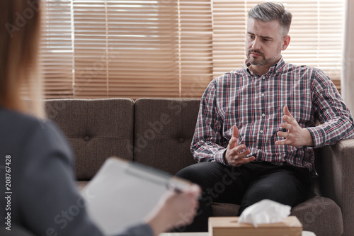 Фото: Handsome man gesticulating while talking to his psychologist during a therapy Handsome man gesticulating while talking to his psychologist during a therapy