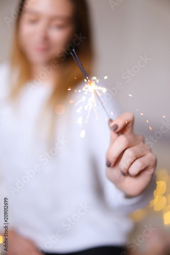 Фото: Blurred photo of young happy girl sitting with closeup bengal light. Concept of handmade decorations for Christmas and New Year holidays. Blurred photo of young happy girl sitting with closeup bengal light. Concept of handmade decorations for Christmas and New Year holidays.