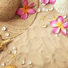 summer background, summer hat, seashells and tropical flowers on sand beach. frame with copy space