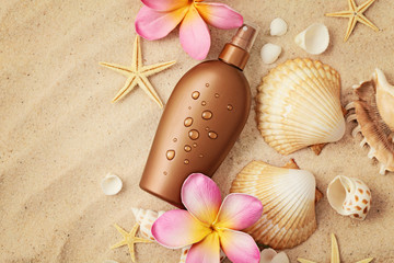 suntan lotion and seashells on sand beach