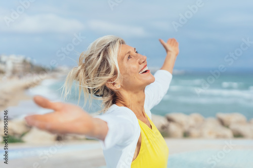 ältere Frau steht mit ausgebreiteten armen am strand und genießt den Urlaub ältere Frau steht mit ausgebreiteten armen am strand und genießt den Urlaub