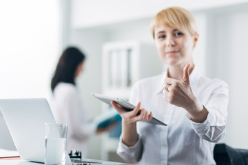 Young employee showing thumbs-up in the office