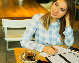 smart woman writing down her ideas and drinking coffe in cafe