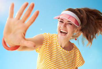 happy healthy woman in yellow shirt against blue sky high five